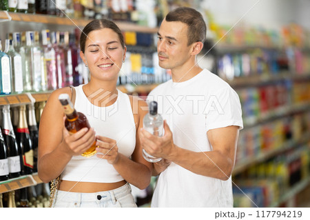 Couple of men and women choosing whiskey and vodka 117794219