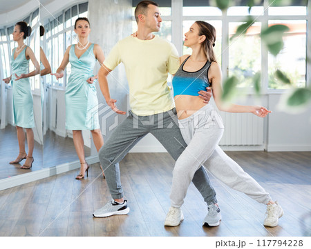 Couple practicing passionate tango guided by female dance instructor in studio 117794228