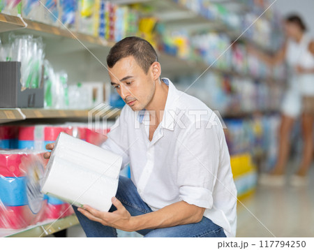 Male customer in store chooses package of toilet paper 117794250