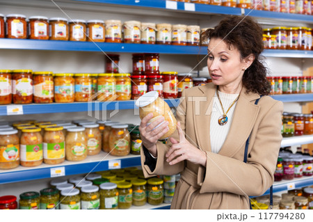 Adult woman chooses sauerkraut in store Adult woman chooses sauerkraut in store 117794280