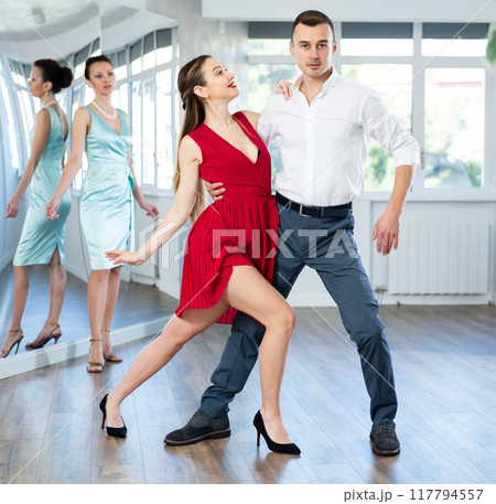 Couple in stage costumes learns tango dancing during individual lesson Couple in stage costumes learns tango dancing during individual lesson 117794557