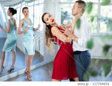 Couple in stage costumes learns tango dancing during individual lesson 117794658