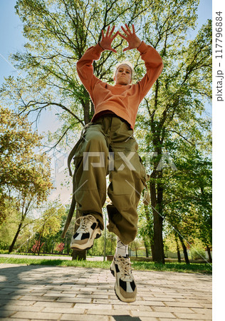 Individual captured mid-jump in outdoor park, surrounded by lush green trees, wearing casual, comfortable clothing perfect for active movement Individual captured mid-jump in outdoor park, surrounded by lush green trees, wearing casual, comfortable clothing perfect for active movement 117796884