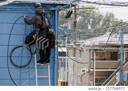 雨の日にアパートの電気工事をする作業員の後ろ姿 雨の日にアパートの電気工事をする作業員の後ろ姿 117798072