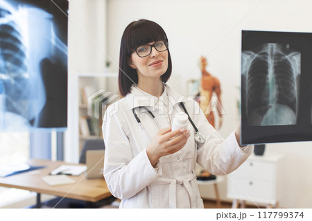 Female doctor examining x-ray and holding medication bottle 117799374