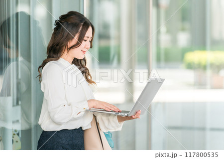 ビジネス街でノートパソコンを使うオフィスカジュアルのOL・ビジネスウーマン 117800535