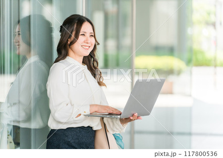 ビジネス街でノートパソコンを使うオフィスカジュアルのOL・ビジネスウーマン 117800536