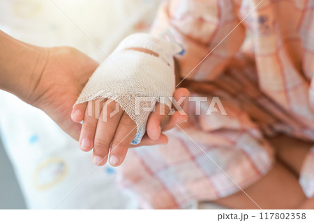 Mother holds hand of her sick child with concern in Hospital ward. tube of normal saline infusion at hospital because it is influenza A. Concept about treatment, emergency, medical, chemotherapy, sick 117802358