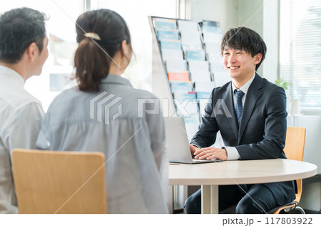 ショールーム・商談スペースで接客する若いアジア人ビジネスマンと客の夫婦 117803922