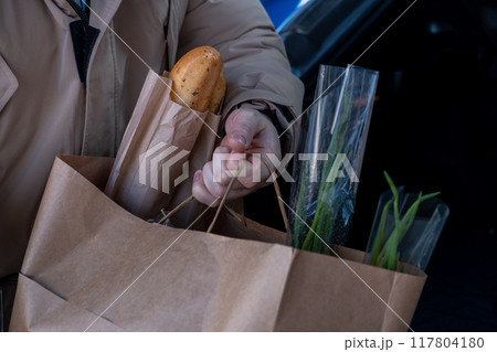 Man Loading Groceries into Car Trunk 117804180