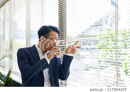 ブラインド越しに外を見つめる男性 117804297