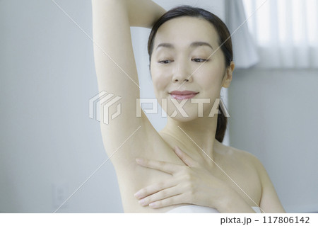 リビングで脇のお手入れをする若い女性 117806142