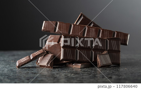 Broken bitter chocolate bar on a black background. 117806640