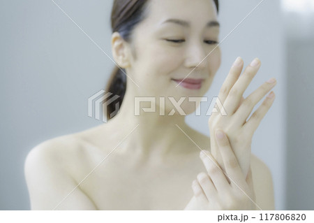 ハンドクリームを塗る若い女性の手元のアップ 117806820