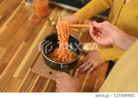 Cropped shot of young couple sharing a bowl of instant noodles enjoying a casual meal in kitchen 117806985