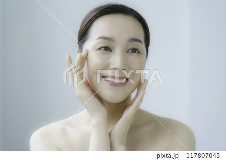 顔のお肌のお手入れをする若い女性 117807043