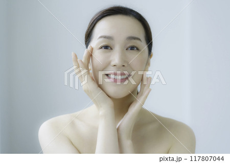 顔のお肌のお手入れをする若い女性 117807044