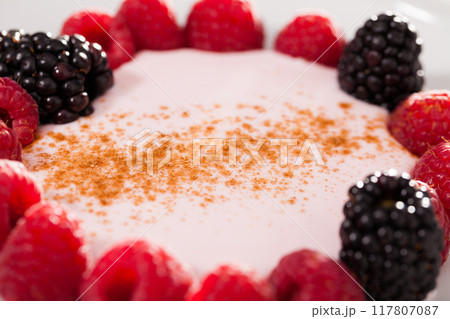 Raspberries and blackberries laid out on a white plate in circle with yogurt and cinnamon Raspberries and blackberries laid out on a white plate in circle with yogurt and cinnamon 117807087