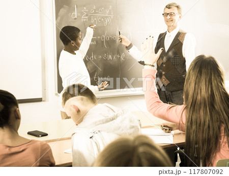 Student from Africa answers on the board during a math lesson Student from Africa answers on the board during a math lesson 117807092