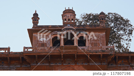Varanasi, India. Close-up View On Roof Top Of Chet Singh Ghat, With Magnificent Fort-like Palace, Is Named After Chait Singh. Blue Sunset Sky At Evening . Close-up View On Old Red Wall Chet Singh Fort Varanasi, India. Close-up View On Roof Top Of Chet Singh Ghat, With Magnificent Fort-like Palace, Is Named After Chait Singh. Blue Sunset Sky At Evening . Close-up View On Old Red Wall Chet Singh Fort 117807198