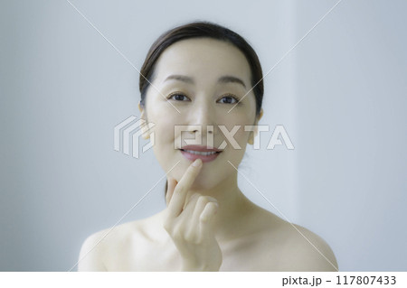 唇に手を当てる若い女性 117807433