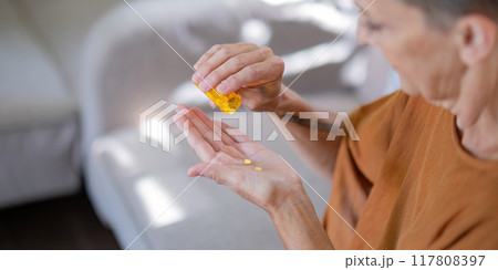 Elderly Woman Preparing to Take Pills from Bottle at Home 117808397