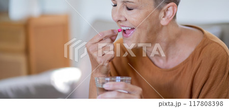 Elderly Woman Taking Medication with Water at Home 117808398