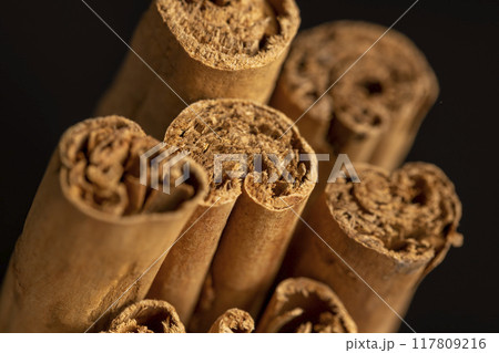 Thick wooden cinnamon on a black slate board 117809216