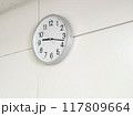 白い壁に掛かったアナログ壁掛け時計 117809664