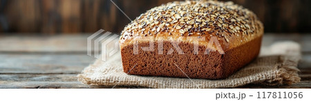 Freshly Baked Multigrain Bread Loaf on Rustic Wooden Table with Burlap Cloth 117811056