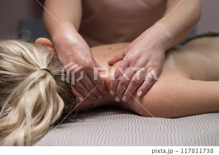 A woman undergoing a massage of the cervical-collar area.  117811738