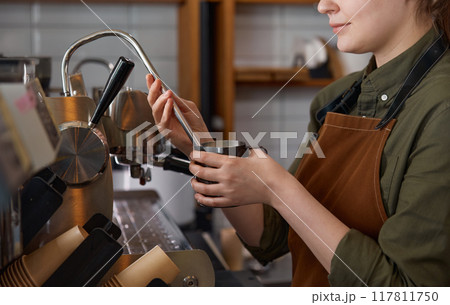Closeup cropped shot of barista preparing latte with milk foam on coffee machine Closeup cropped shot of barista preparing latte with milk foam on coffee machine 117811750