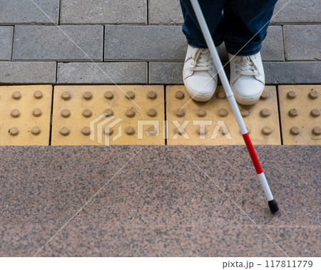 Blind woman walking outdoors using a tactile cane. Blind woman walking outdoors using a tactile cane. 117811779