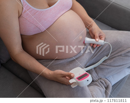 Close-up of a pregnant woman's belly using a home doppler. Blank screen. Close-up of a pregnant woman's belly using a home doppler. Blank screen. 117811811