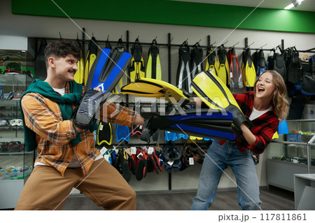 Young joyful man and woman couple fighting flippers at shop store 117811861