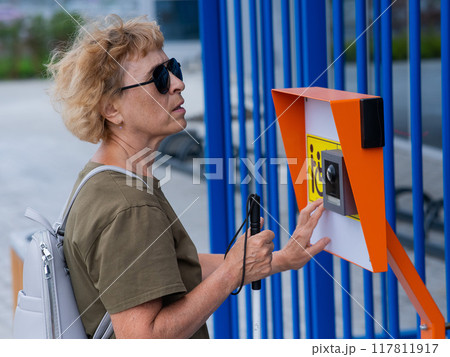 An elderly blind woman reading a text in braille. Button for calling help for people with disabilities. An elderly blind woman reading a text in braille. Button for calling help for people with disabilities. 117811917