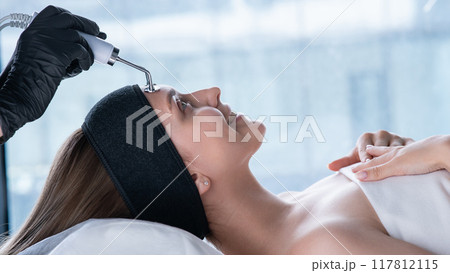 Young caucasian woman on microcurrent therapy procedure. Beautician's office. Young caucasian woman on microcurrent therapy procedure. Beautician's office. 117812115