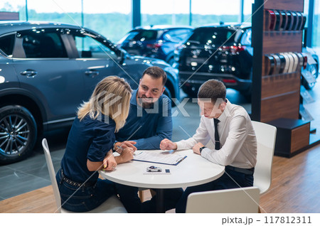 Happy caucasian couple signs a contract for the purchase of a car salon. 117812311