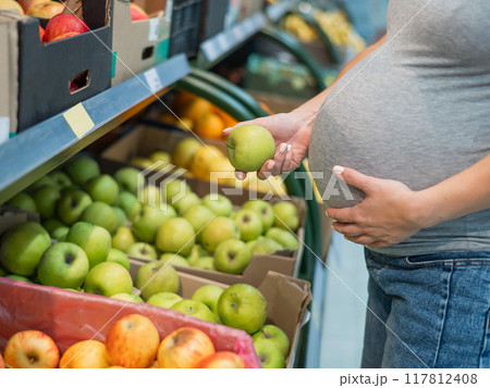 Pregnant woman chooses apples in the store. Pregnant woman chooses apples in the store. 117812408