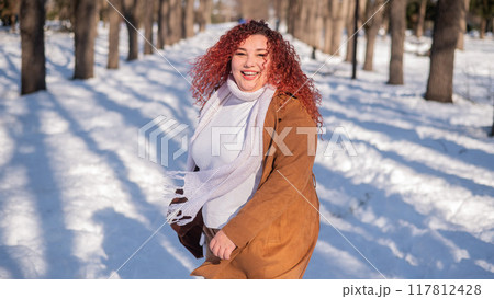 Portrait of an excited red-haired curly fat woman in the park in winter. Portrait of an excited red-haired curly fat woman in the park in winter. 117812428