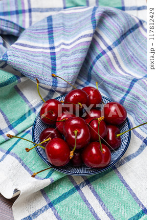 Ripe cherries in a wooden bowl on a wooden white background. Harvesting 117812429