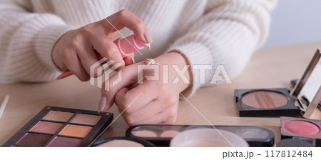 Close-up of makeup artist's hands among cosmetics.  117812484