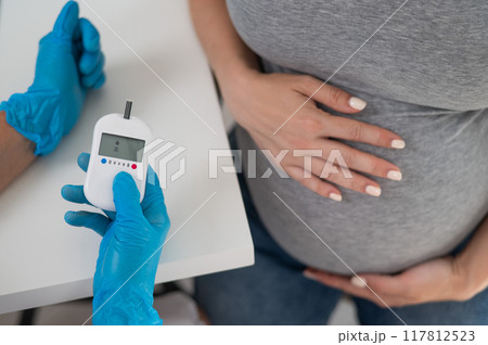 The doctor checks the blood sugar level of a pregnant patient. Gestational diabetes.  117812523