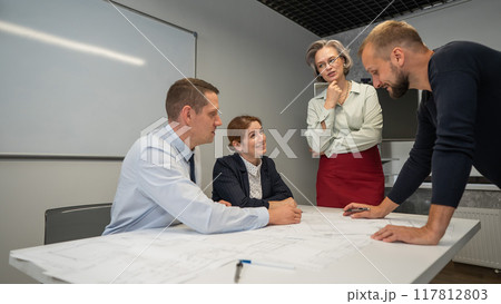 The female boss evaluates the work of subordinates. Designers engineers at a meeting.  117812803