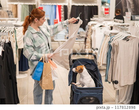 Caucasian woman shopping with her Jack Russell terrier dog in a stroller. 117812898