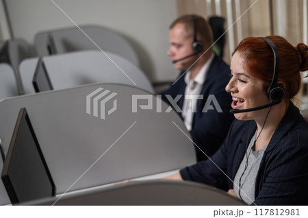 Two friendly call center employees answer customers by phone. Man and woman woman talking on a headset in the office. Two friendly call center employees answer customers by phone. Man and woman woman talking on a headset in the office. 117812981