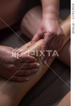 Close-up of a woman's leg massage in a salon. Vertical photo. Close-up of a woman's leg massage in a salon. Vertical photo. 117813018