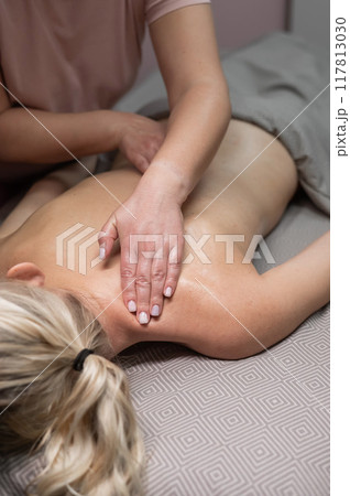 A woman undergoing a massage of the cervical-collar area. Vertical photo. A woman undergoing a massage of the cervical-collar area. Vertical photo. 117813030
