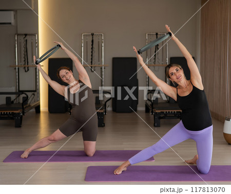 Two pregnant women doing yoga. Exercises with a gymnastic circle for Pilates.  117813070