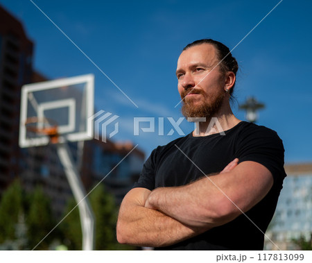 Portrait of a Caucasian bearded man on a basketball court outdoors.  117813099